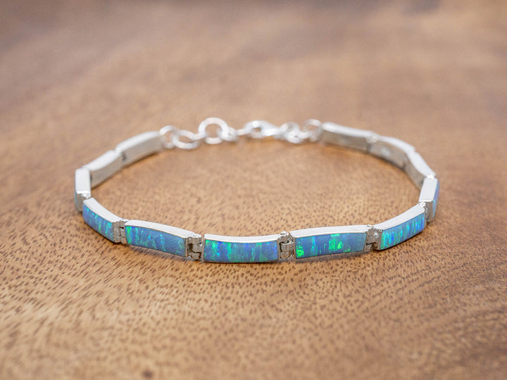 A sterling silver bracelet with slightly curved rectangular link, each set with blue opal.