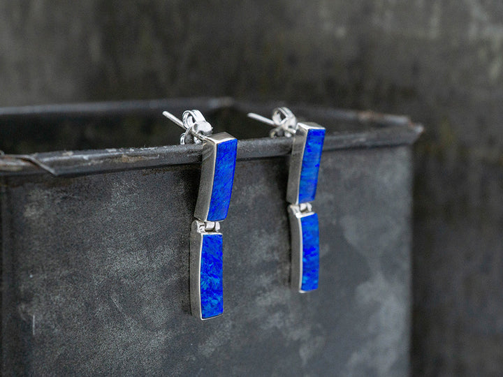 A pair of sterling silver post earrings with 2 rectangular links of dark blue opal.