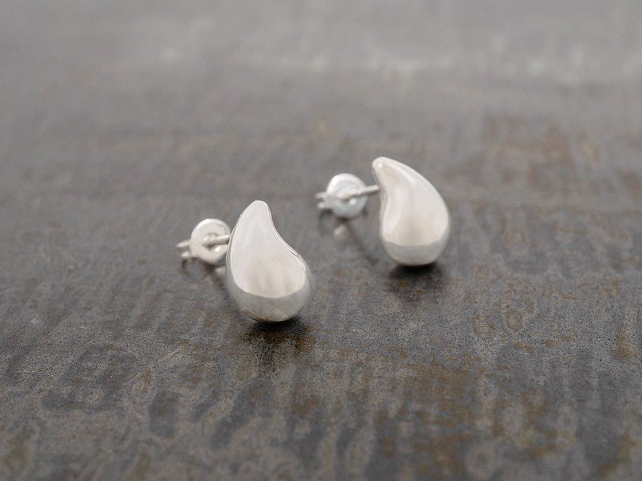 A pair of small, comma shaped stud earrings made of sterling silver.