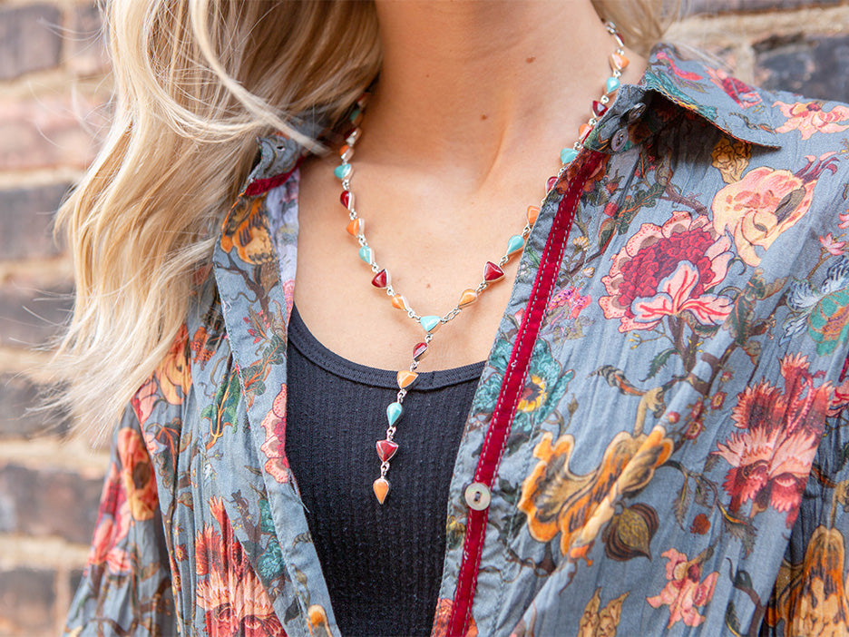 A model wearing a sterling silver lariat necklace made with teardrop and trillion cut multi-colored stones.