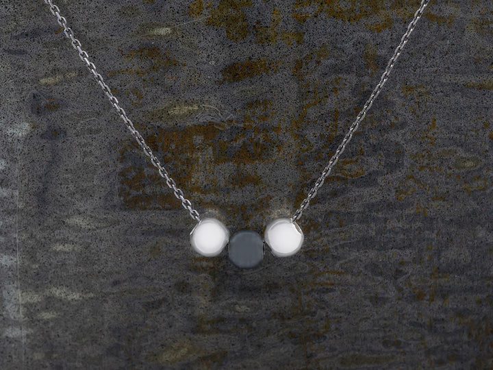 An oxidized chain featuring three center beads; two that are bright silver and an oxidized bead in the center.