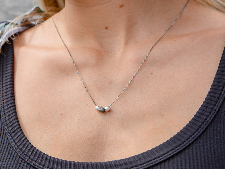 An oxidized chain featuring three center beads; two that are bright silver and an oxidized bead in the center.