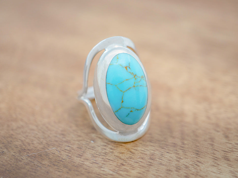 A large, oval sterling silver statement ring with a turquoise stone in the center.
