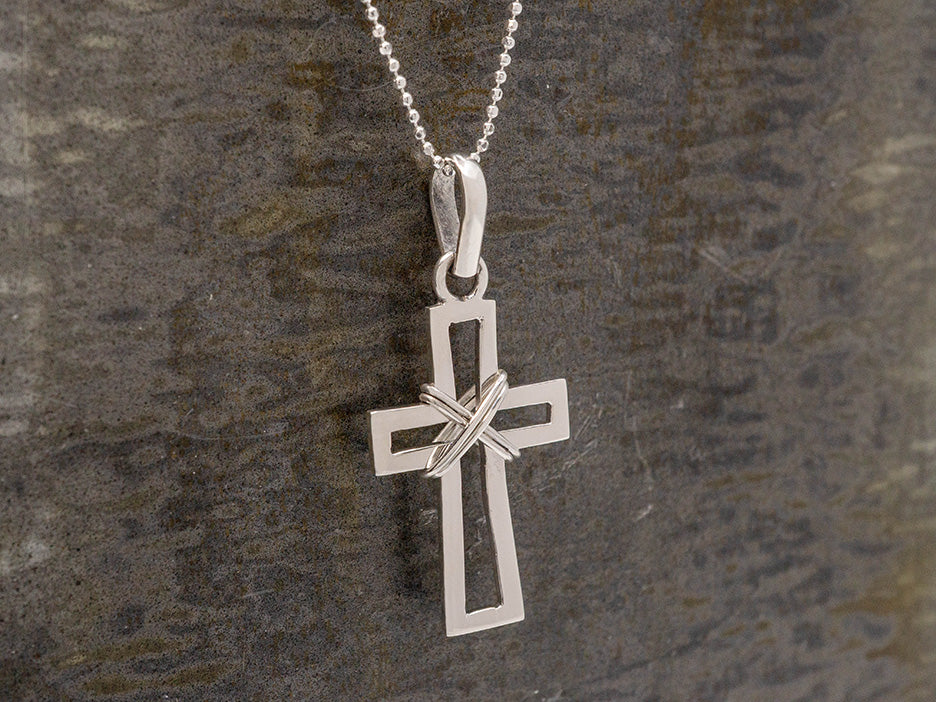 A cross outline pendant with wire wrapped around the center.