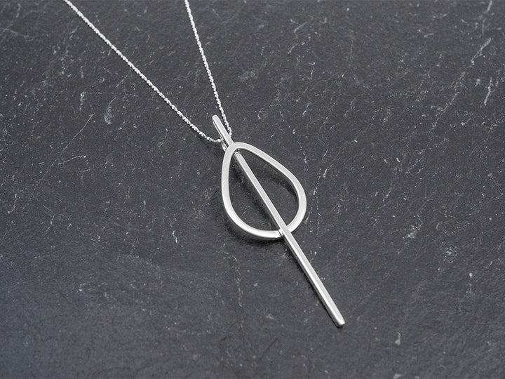 A bold geometric pendant hanging on a dainty sterling silver rope cut chain.
