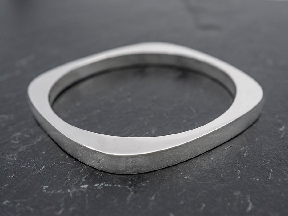 A sterling silver bangle with a soft square exterior shape and a circle cut out in the center.