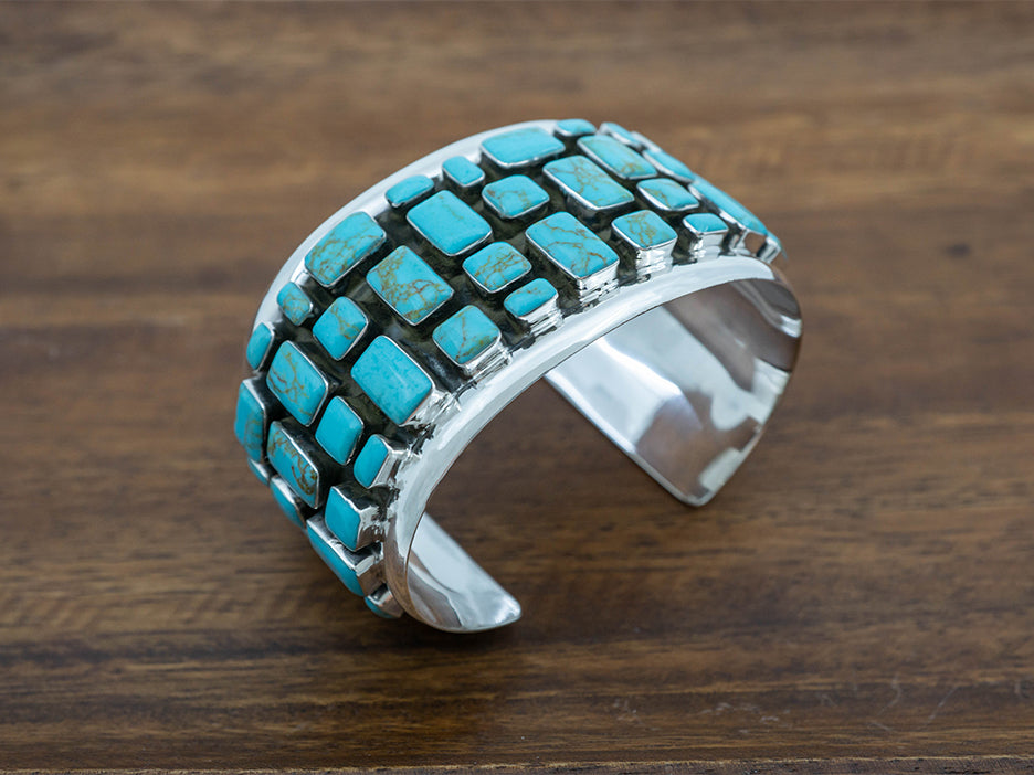 Wide sterling silver cuff with turquoise stones laid out in a cobblestone pattern.