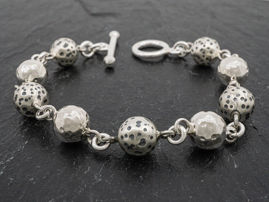 Sterling silver bracelet with alternating hammered and dalmation-style beads and a toggle closure.