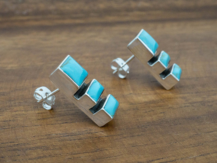 A sterling silver post earring featuring three turquoise stones.