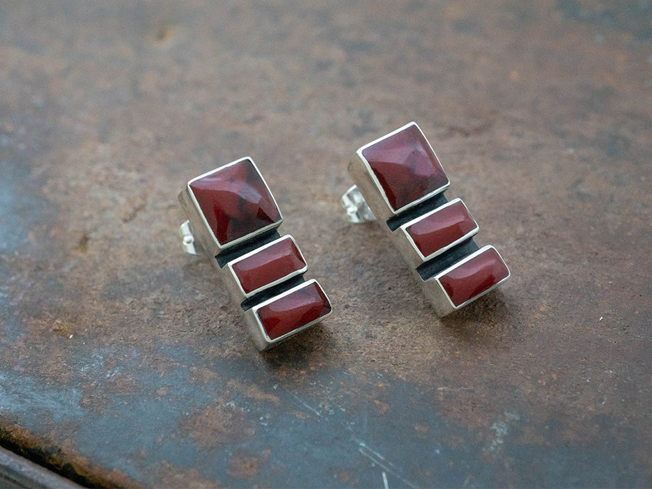 A sterling silver earring featuring three red jasper stones.