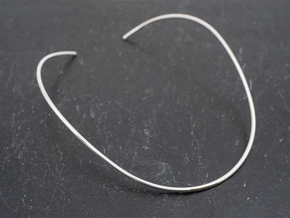 A flexible sterling silver choker that is made to conform to the shape of a woman's neckl