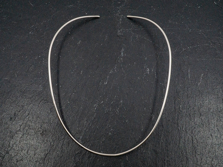 A flexible sterling silver choker that is made to conform to the shape of a woman's neck.