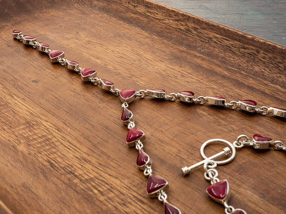 A sterling silver lariat necklace made with teardrop and trillion cut red jasper stones.