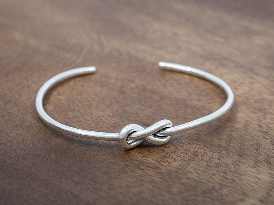 Silver knot cuff bracelet on a wooden surface