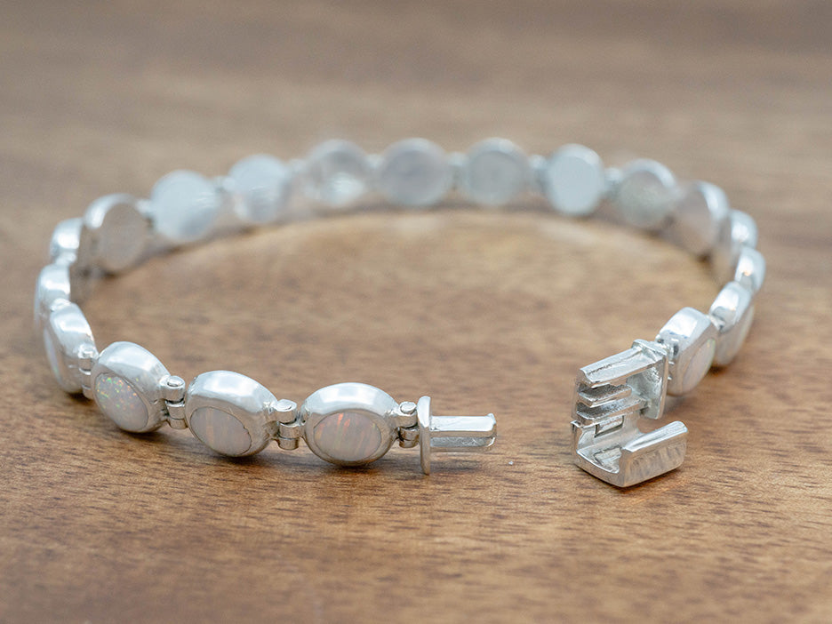 a petite bracelet of white opal cabochons set in sterling silver with a book binder's clasp