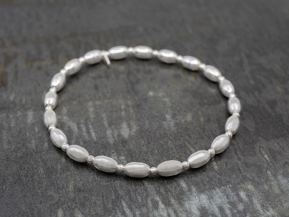 A sterling silver stretch bracelet featuring alternating spherical and elongated beads