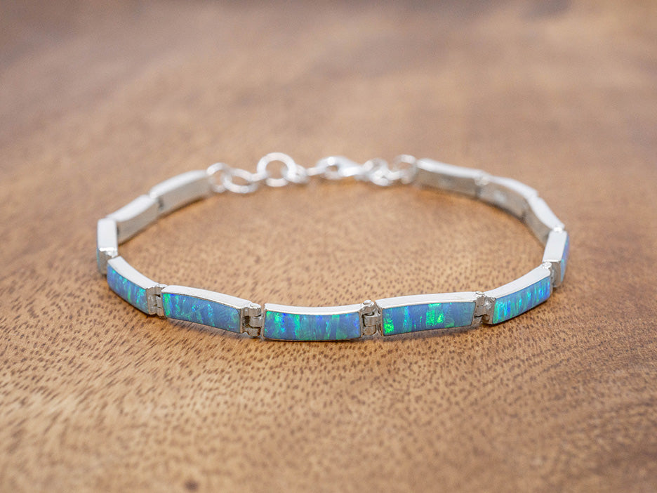 A sterling silver bracelet with slightly curved rectangular link, each set with blue opal.