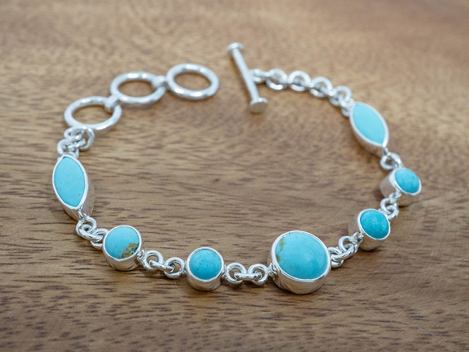 Silver bracelet with turquoise stones on a wooden surface