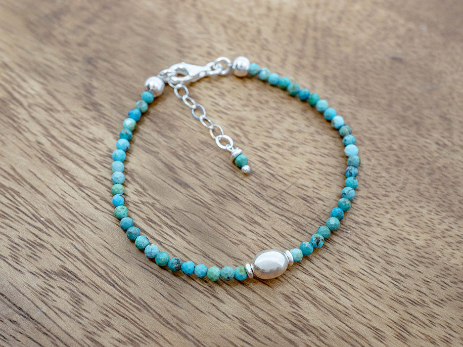 Turquoise beaded bracelet with silver clasp on a wooden surface