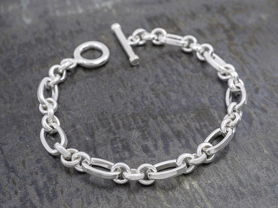 a heavy silver bracelet with alternating oval and circle links and a toggle closure