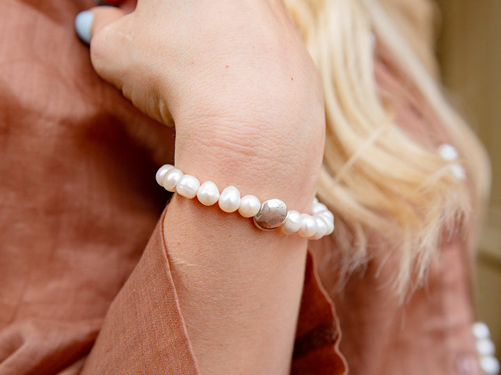 woman wearing a pearl bracelet with a silver bead at the center