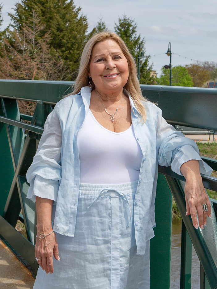 woman wearing a light blue blouse over a white tank top