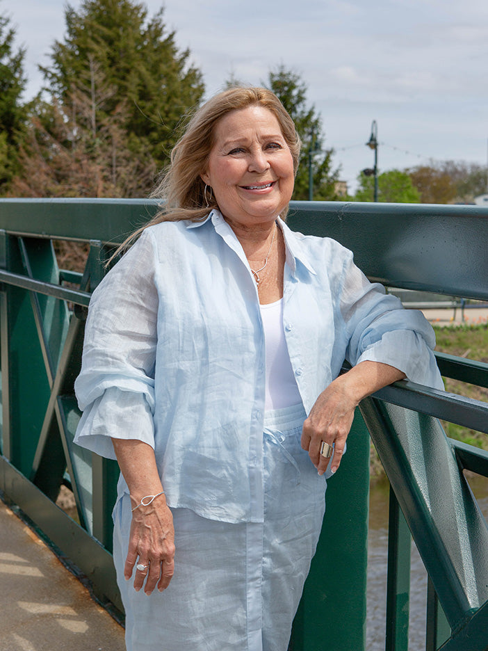 woman wearing a light blue blouse over a white tank top