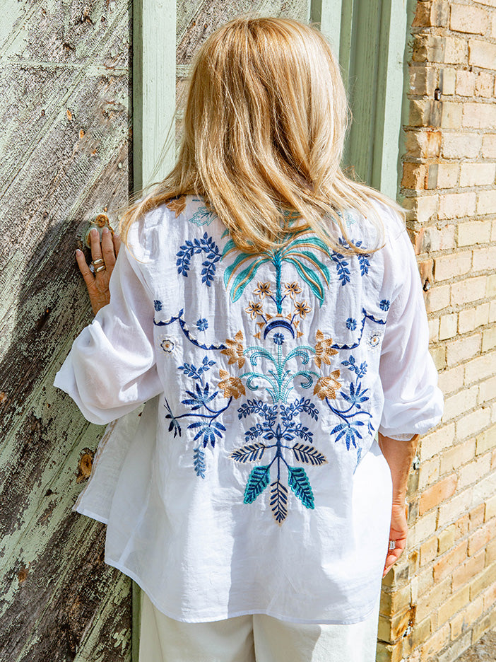 woman wearing white blouse with embroidered details on the back