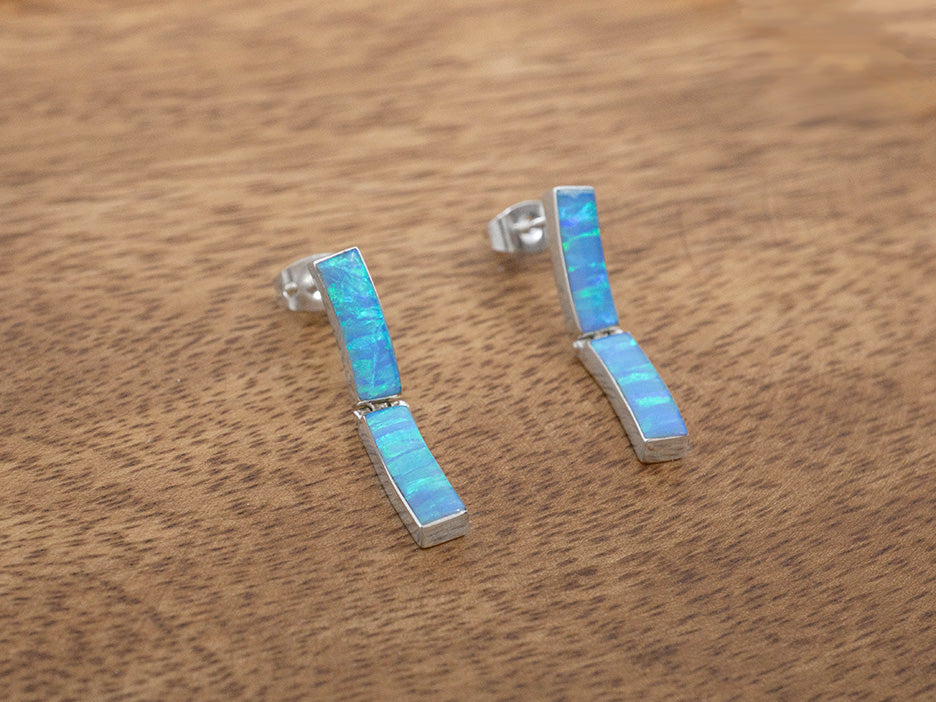 A pair of sterling silver earrings on posts. Each earring has two slightly curved rectangular links set with blue opals.