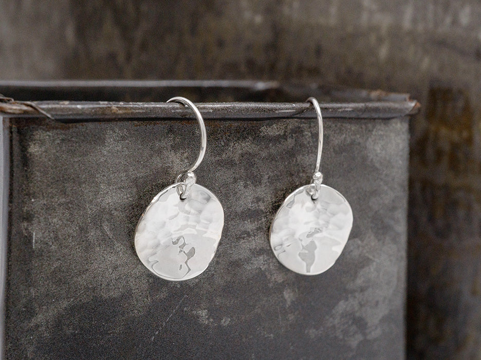 Sterling silver hammered wavy disc earrings on hook.