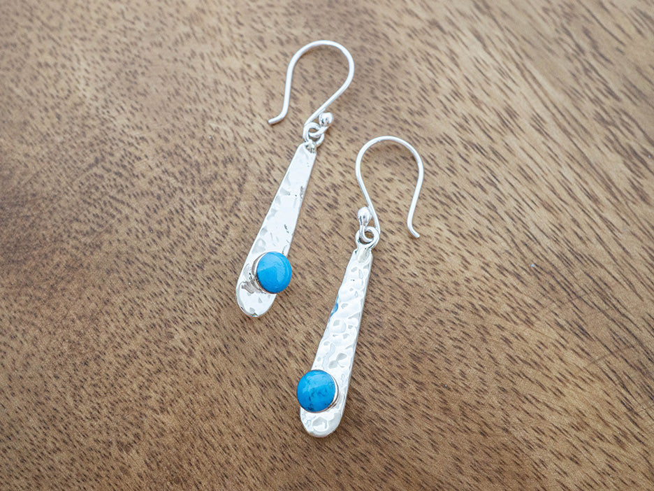 Hammered Silver earrings with turquoise stones on a wooden surface