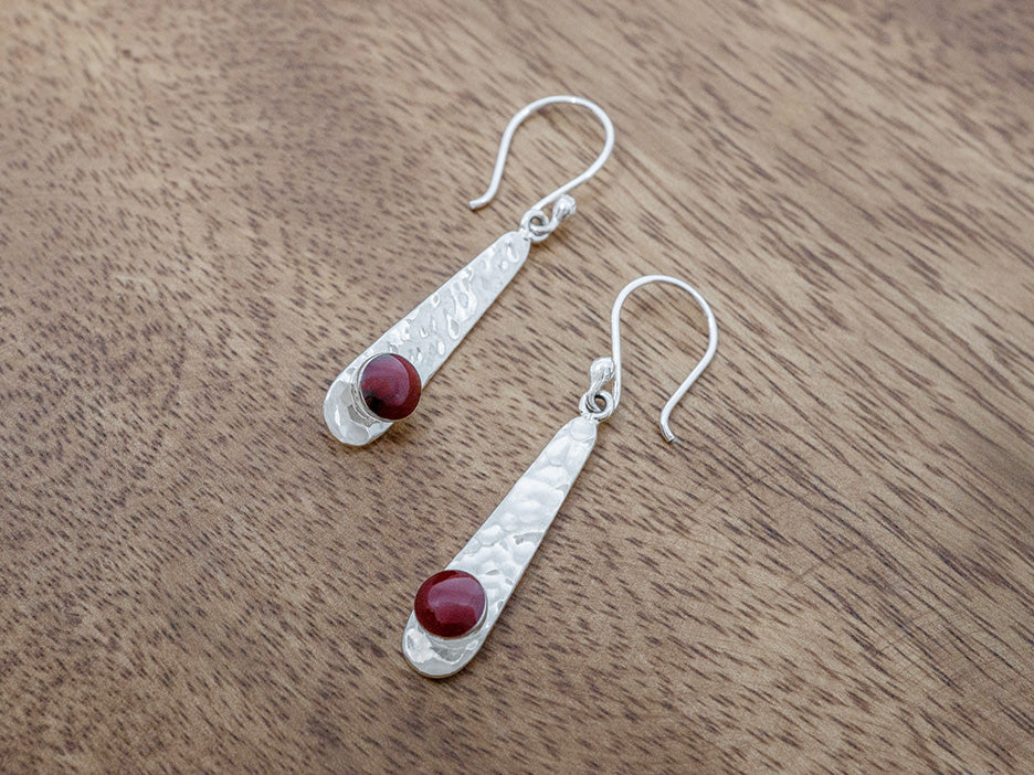 Silver earrings with red stones on a wooden surface