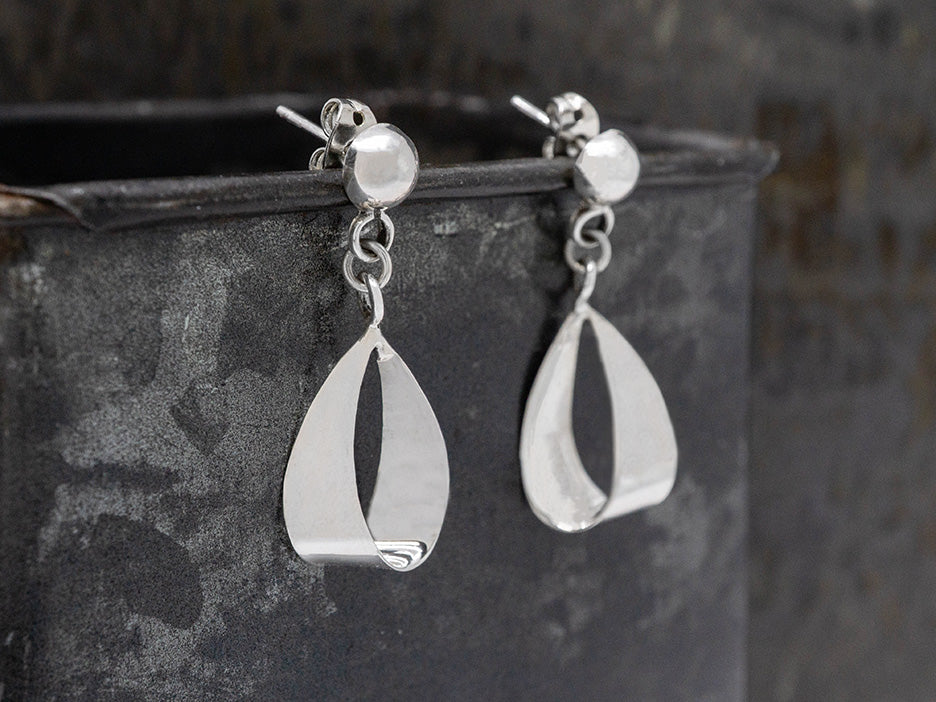 Silver teardrop earrings on a dark surface
