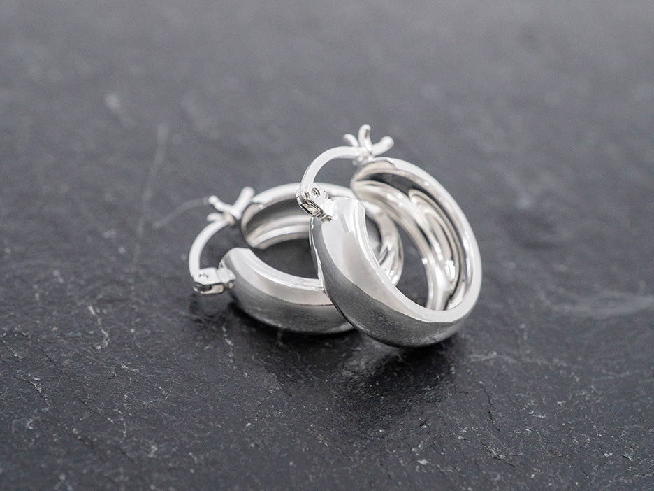 Pair of silver hoop earrings on a dark surface