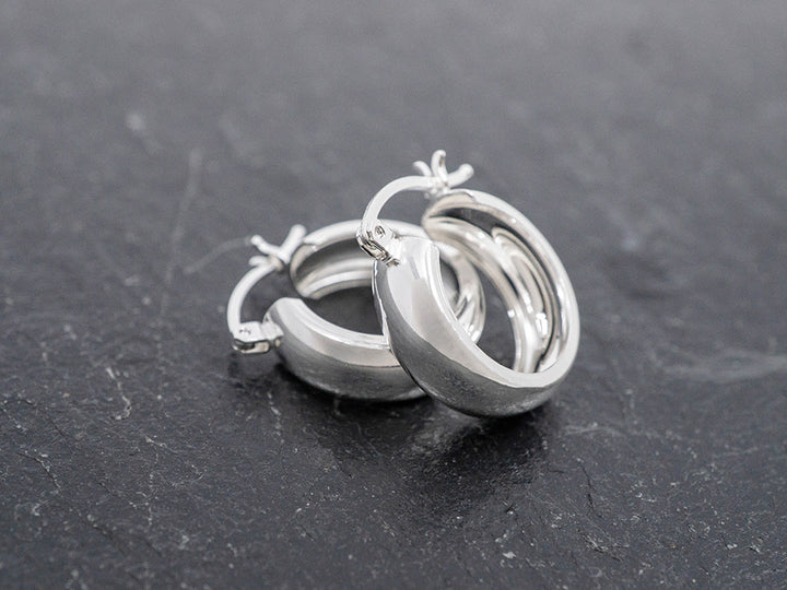 Pair of silver hoop earrings on a dark surface