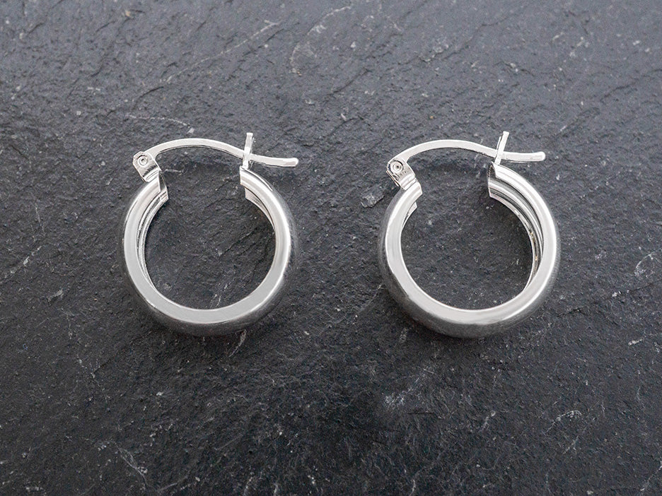 Pair of silver hoop earrings on a dark slate surface