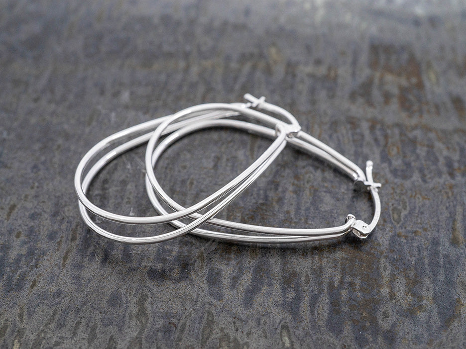 Silver hoop earrings on a textured gray surface