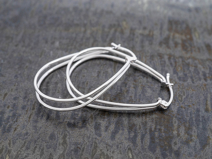 Silver hoop earrings on a textured gray surface