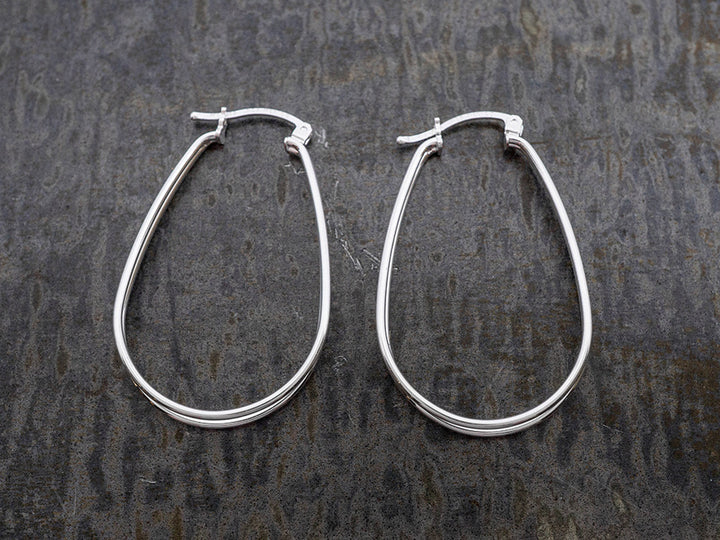 Pair of silver hoop earrings on a textured dark surface