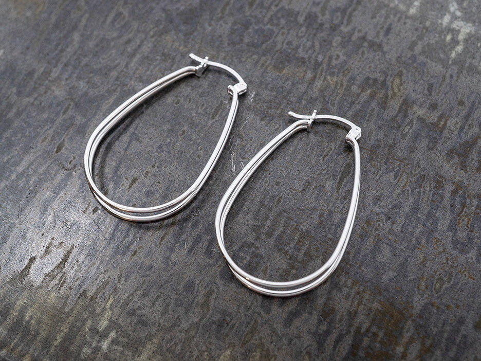 Pair of silver hoop earrings on a textured dark surface