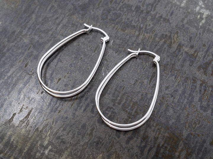Pair of silver hoop earrings on a textured dark surface