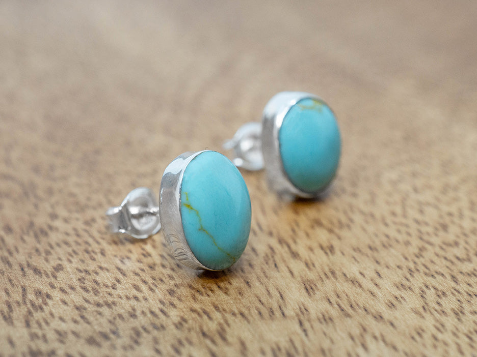 Turquoise stud earrings on a wooden surface