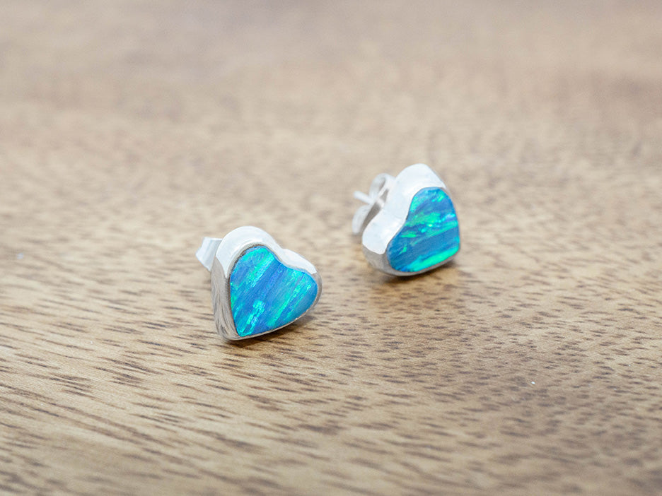 Heart-shaped opal earrings on a wooden surface