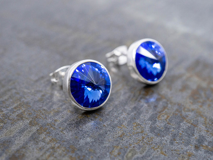 Silver earrings with blue crystals on a textured gray surface