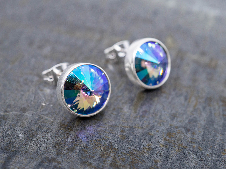 Silver earrings with colorful crystals on a textured gray surface