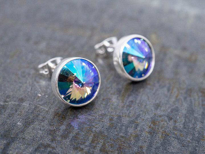 Silver earrings with colorful crystals on a textured gray surface