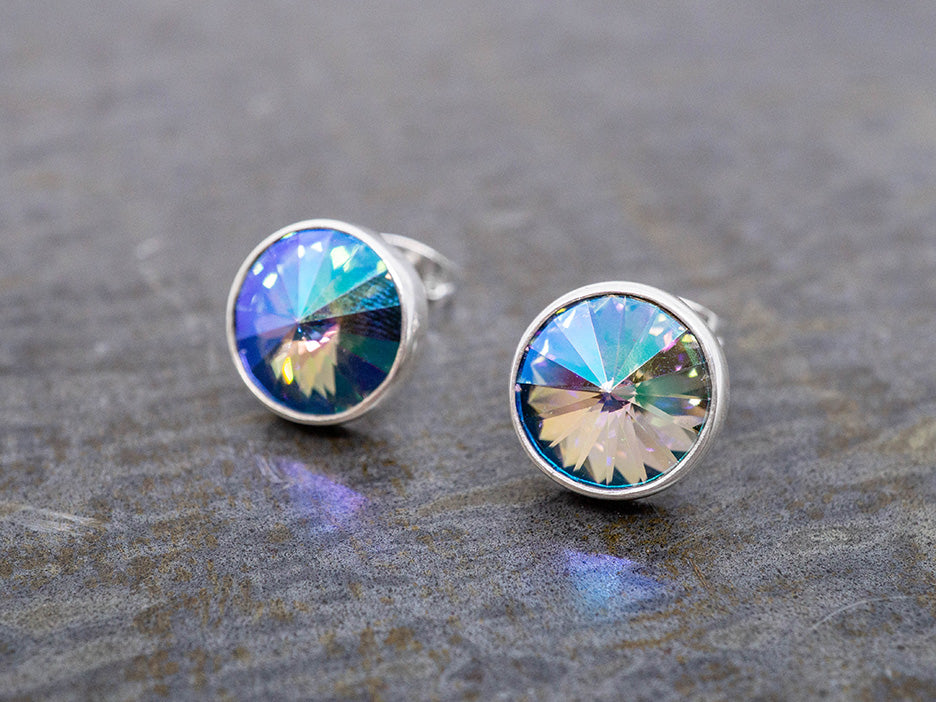 Round stud earrings with colorful crystals on a gray surface