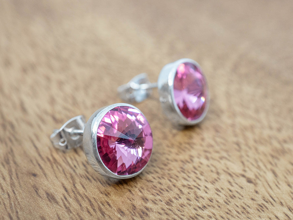 Silver earrings with pink crystals on a wooden surface