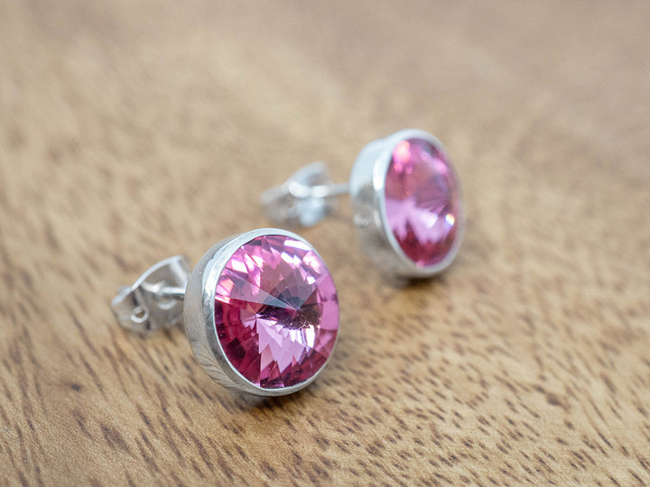 Silver earrings with pink crystals on a wooden surface