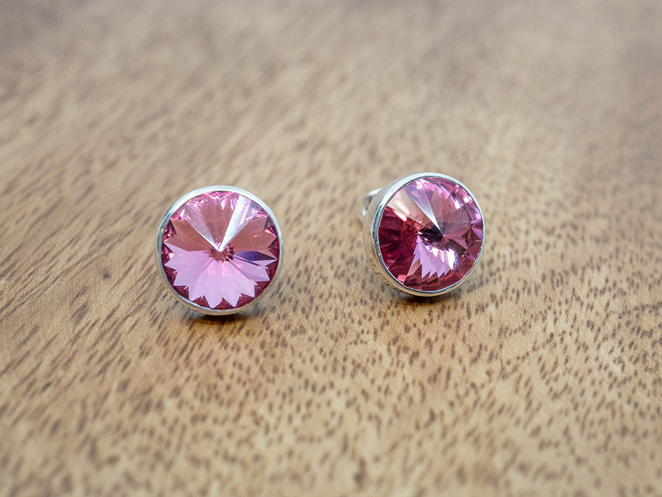 Pair of pink crystal earrings on a wooden surface